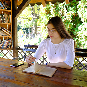 Jeune femme qui lit dasn une bibliothèque sans murs extérieurs, permettant de profiter de la nature qui l'entoure